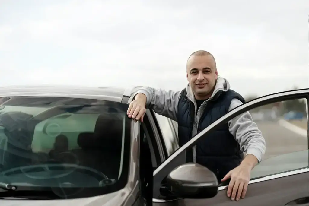 Geschäftsführer Deniz von KFZ Gutachter Experte Hamburg steht neben einem Fahrzeug und berät Kunden rund um Unfallgutachten, Fahrzeugbewertung und Schadengutachten